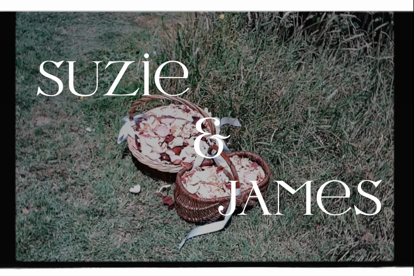 Title frame of the wedding film — Suzie & James over two baskets of petals